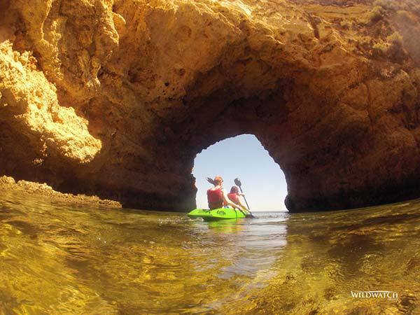 Green kayak with two leaving a cave near Ferragudo