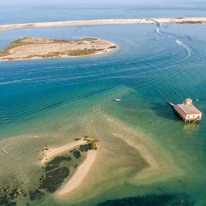 small pieces of sand forming Fuseta Island with flutuant house